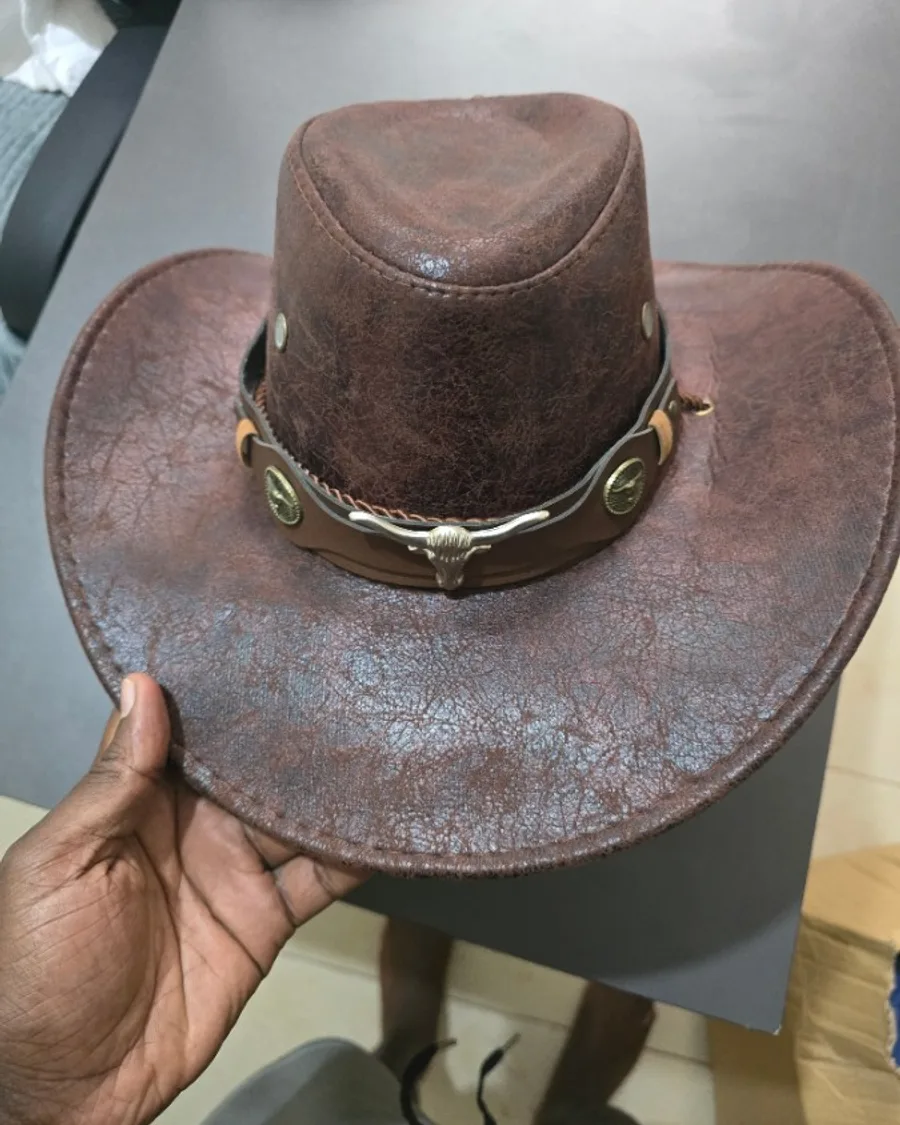 A brown leather cowboy hat held in one hand